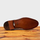 Outsole of Mahogany leather loafer on a wooden surface with a light gray background