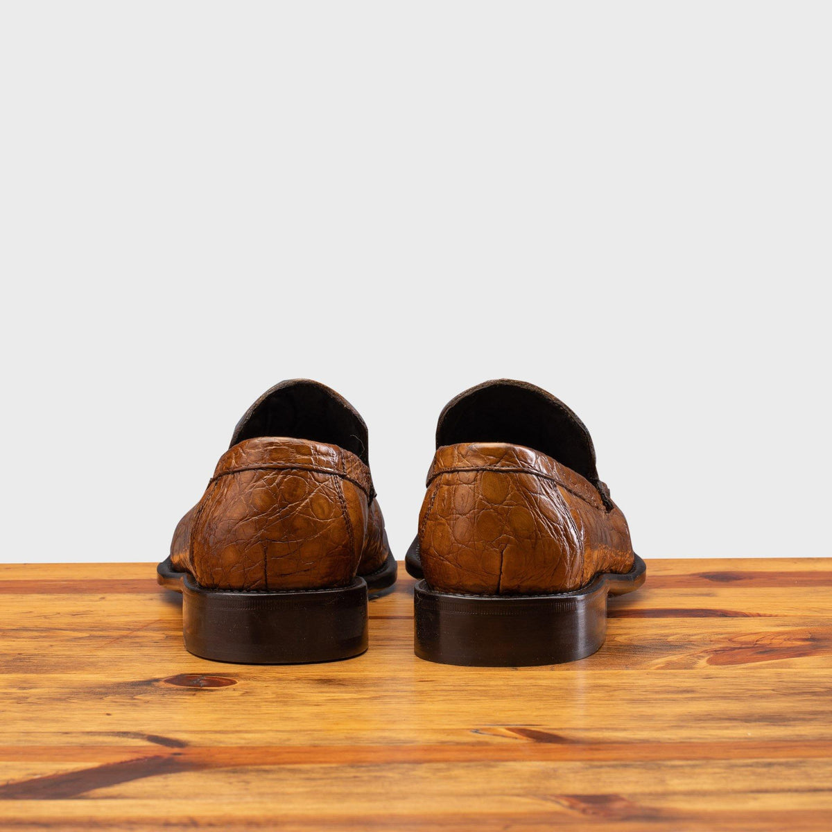 Back Side of Mahogany leather loafer on a wooden surface with a light gray background