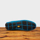 Full Rubber Vibram Outsole of 5303 Calzoleria Toscana Denim Blue Venetian Suede Driver on top of a wooden table