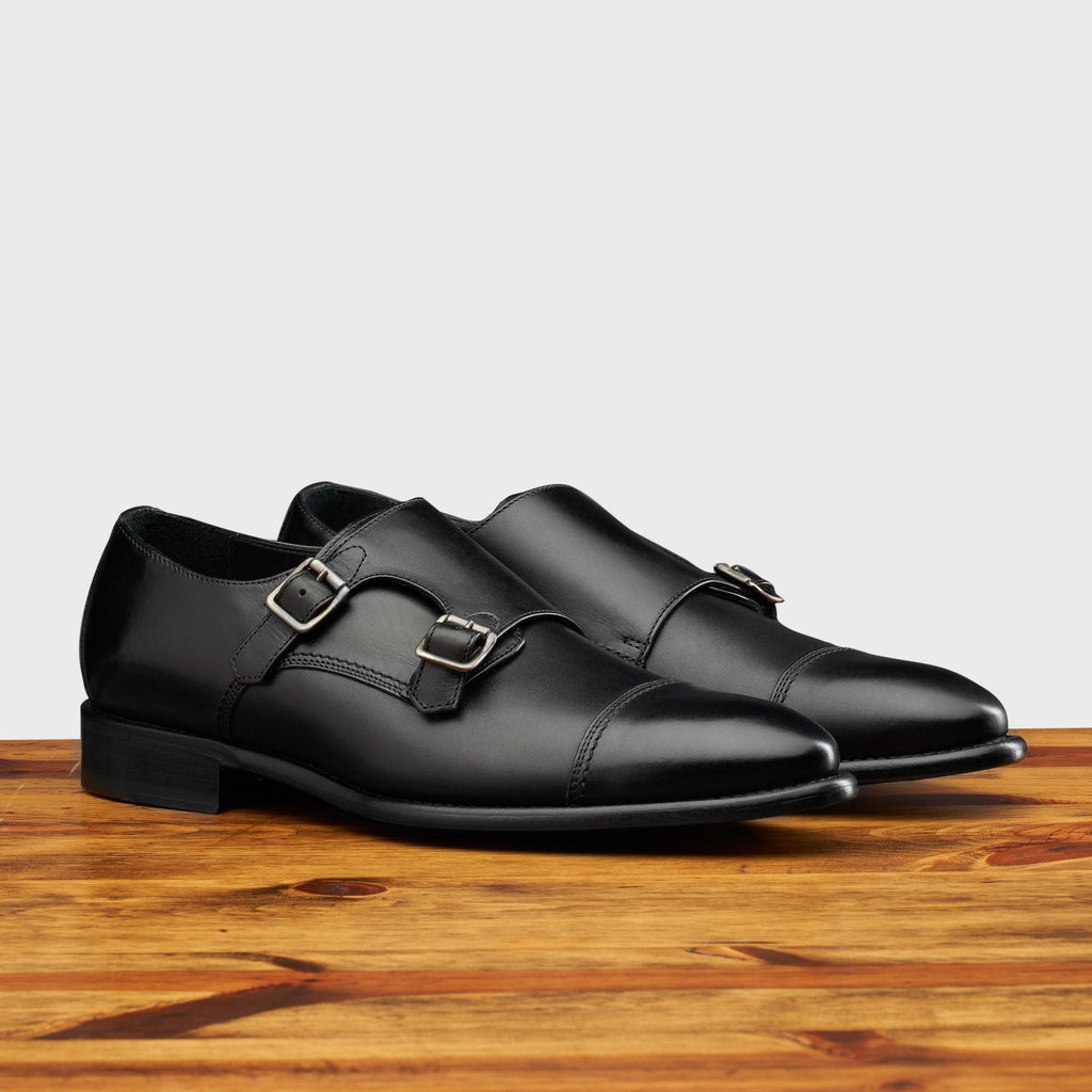 Pair of 6582 Calzoleria Toscana Black Monkstrap Cap Toe on top of a wooden table
