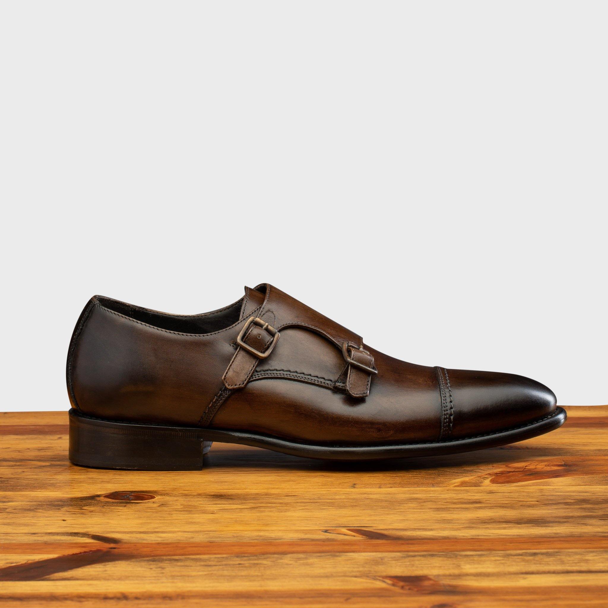 A Moor monk strap cap toe shoe with double straps, displayed on a wooden surface.