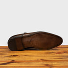 Outsole of a Moor monk strap cap toe shoe with double straps, displayed on a wooden surface.