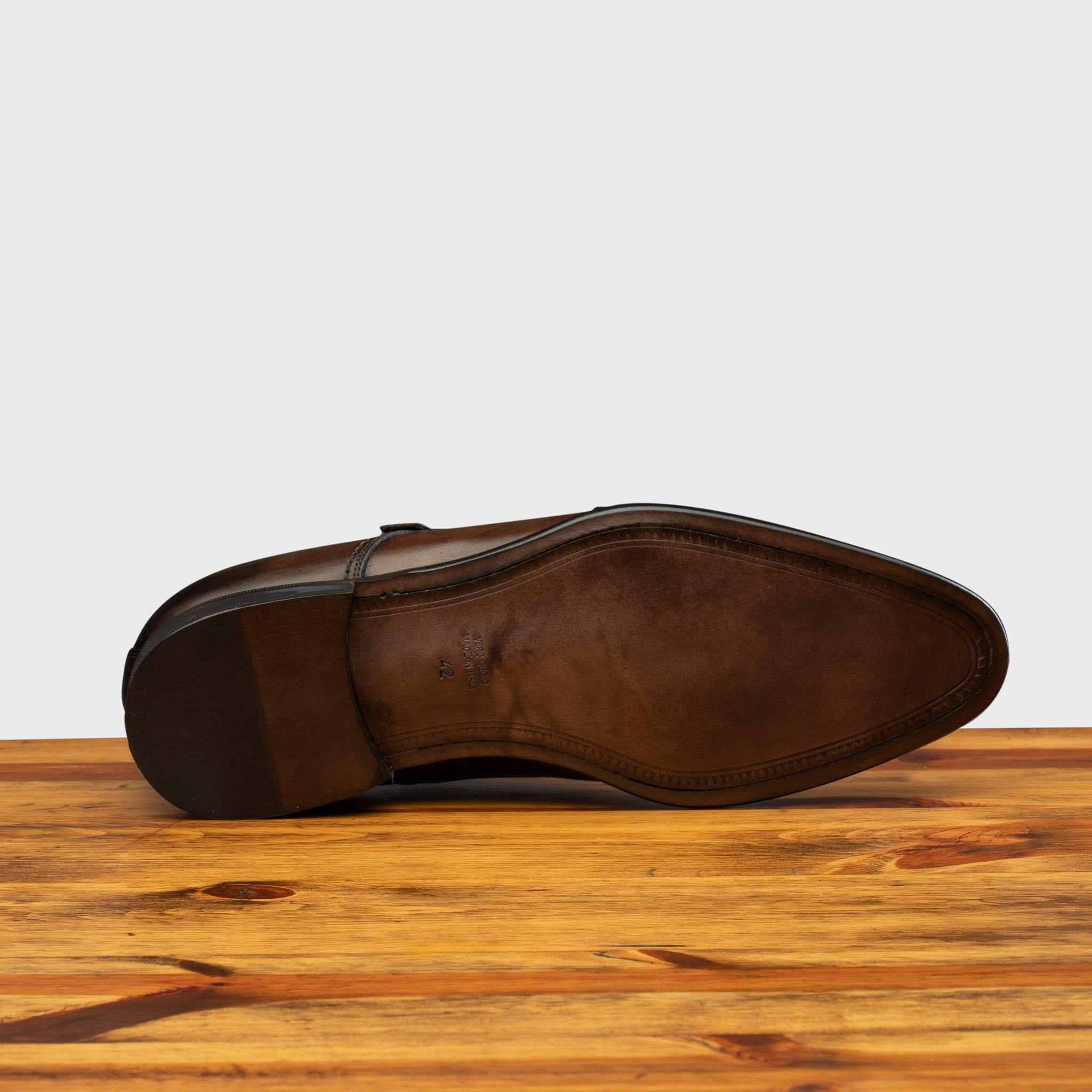 Outsole of a Moor monk strap cap toe shoe with double straps, displayed on a wooden surface.
