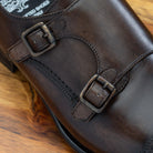 A Moor monk strap cap toe shoe with double straps, displayed on a wooden surface.