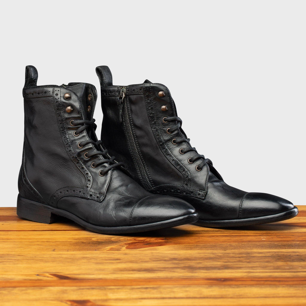 Pair of 7149 Calzoleria Toscana Women's Black Dip-Dyed Diver Combat Boot on top of a wooden table