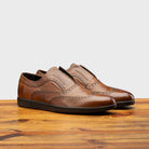 Pair of 7839 Calzoleria Toscana Cerris Elba Slip-On showing perforated wingtip details on top of a wooden table