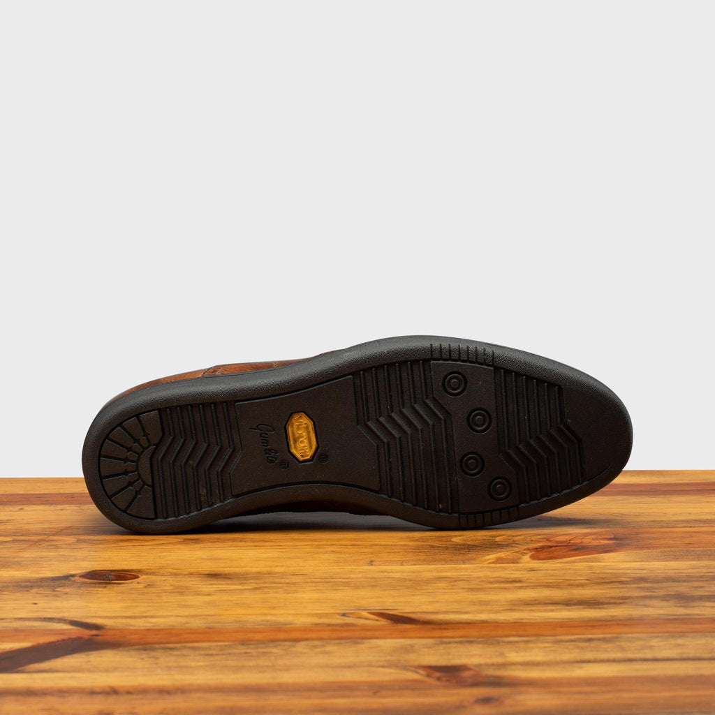 Full Rubber Vibram Gumlite Outsole of 7839 Calzoleria Toscana Elba Slip-On on top of a wooden table