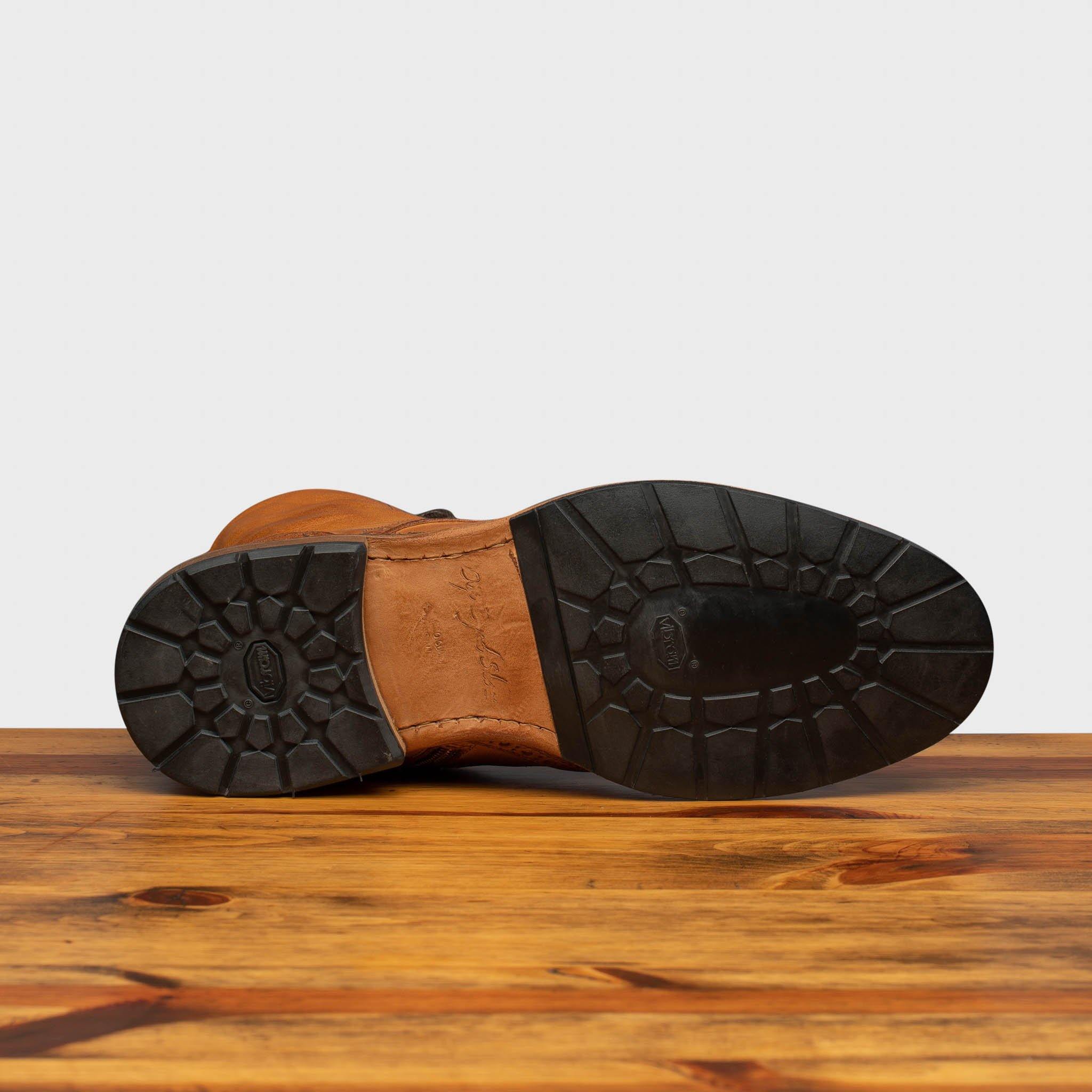 Outsole of Brick leather boots on a wooden surface with a light gray background