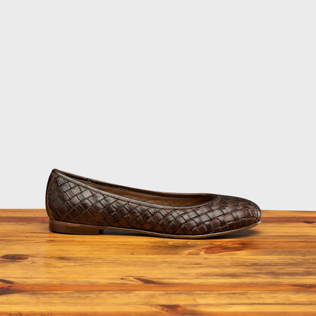 Side profile of B940 Calzoleria Toscana Tobacco Woven Ballerina Flat on top of a wooden table