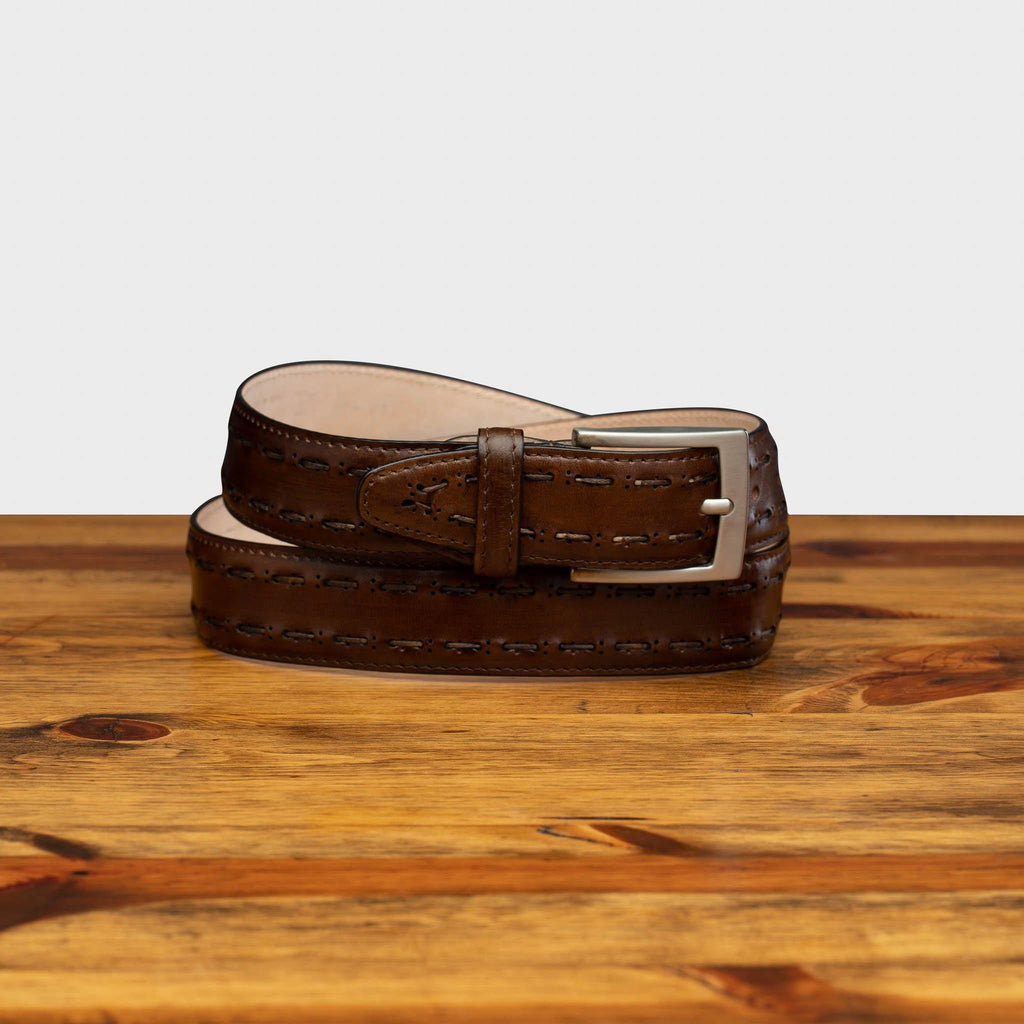 C1482 Calzoleria Toscana Mahogany Stitched Dress Belt curled up on top of a wooden table