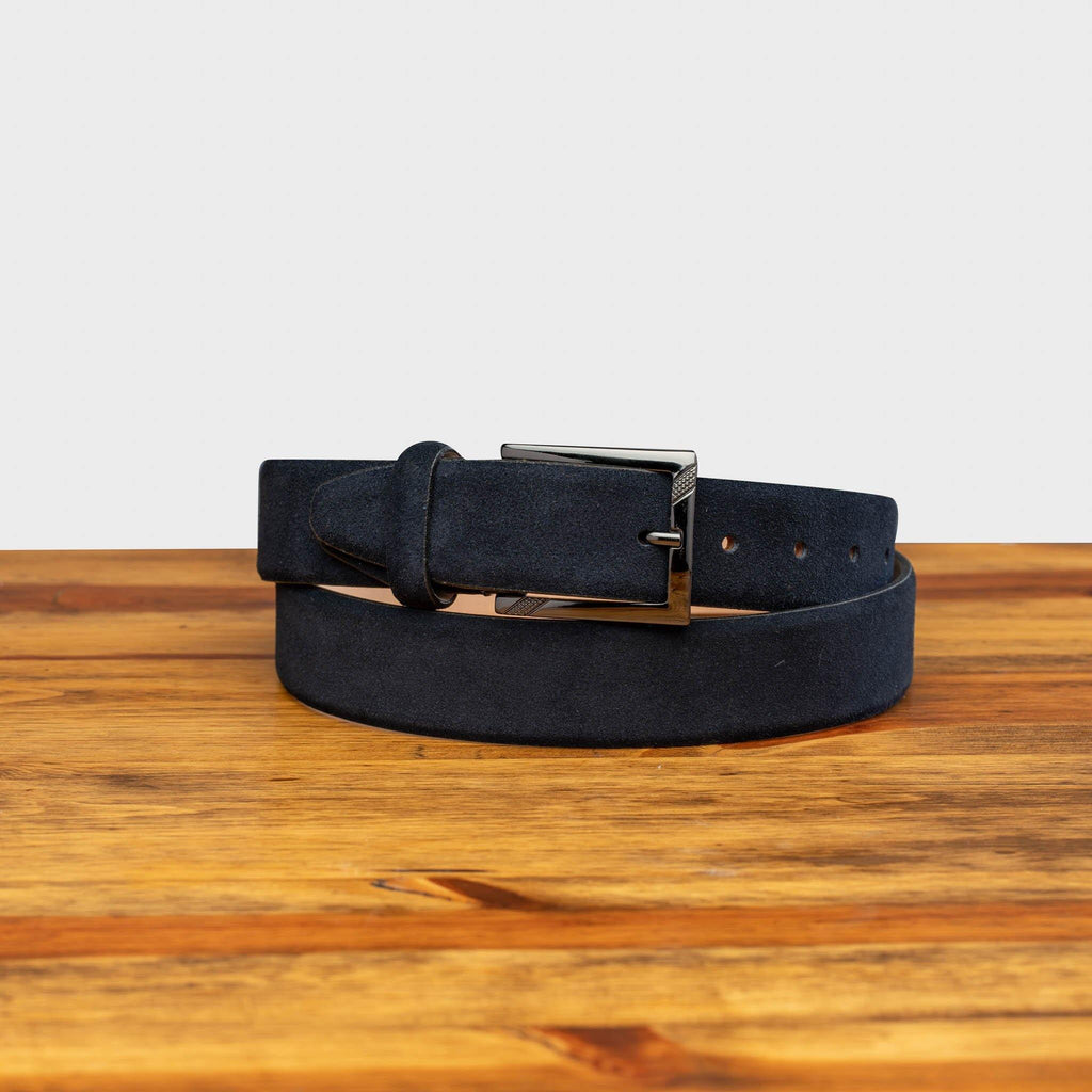 Front profile of C1499-S Calzoleria Toscana Blue Velour Suede Belt curled on top of a wooden table