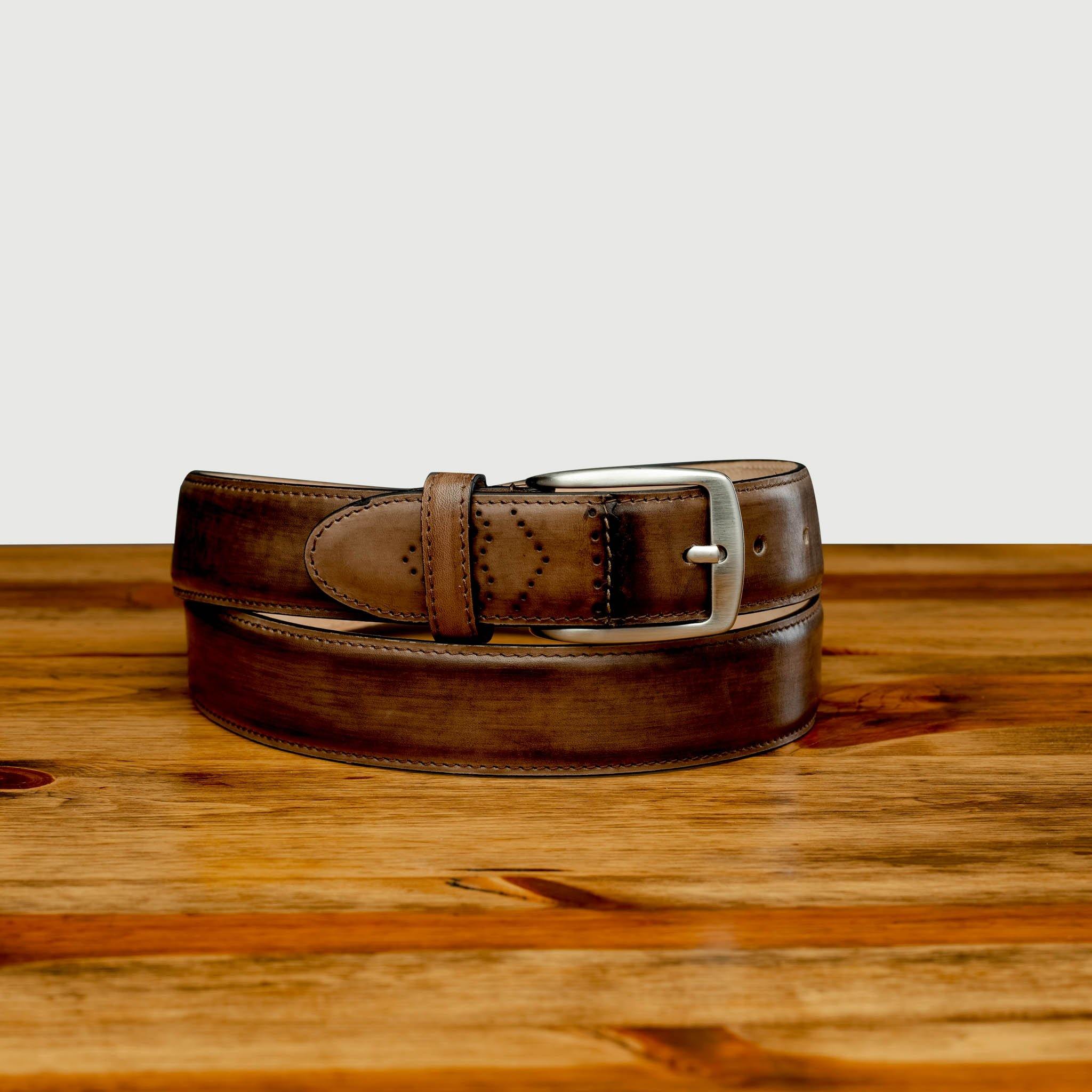 Front profile of C5677 Calzoleria Toscana Brown Artisan Dress Belt curled up on top of a wooden table
