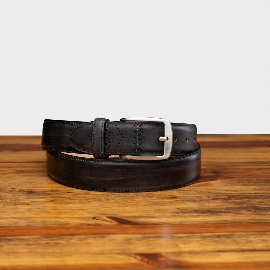 Front profile of C5677 Calzoleria Toscana Graphite Artisan Dress Belt curled up on top of a wooden table