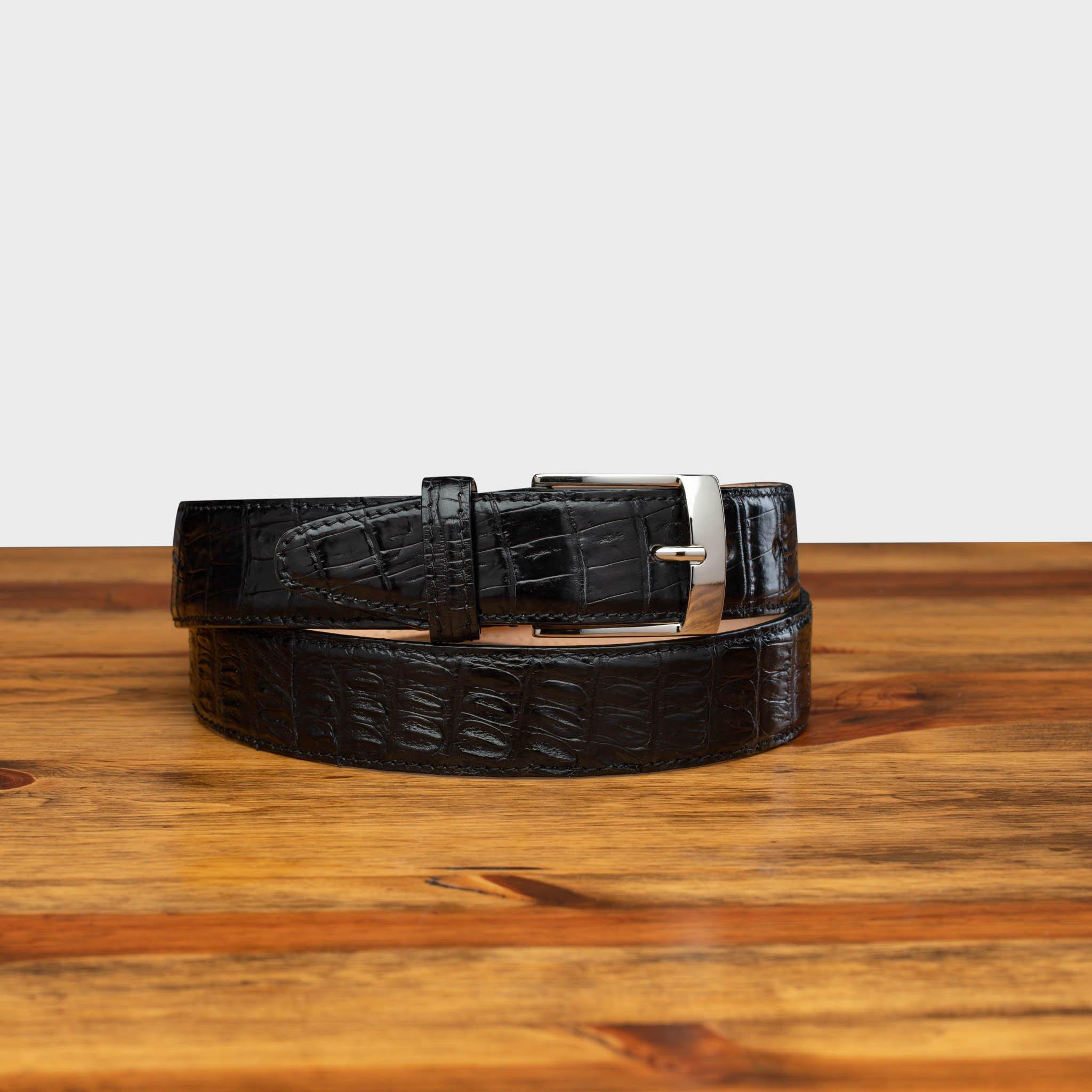 Front profile of C7981 Calzoleria Toscana Black Exotic Hornback Belt on top of a wooden  table