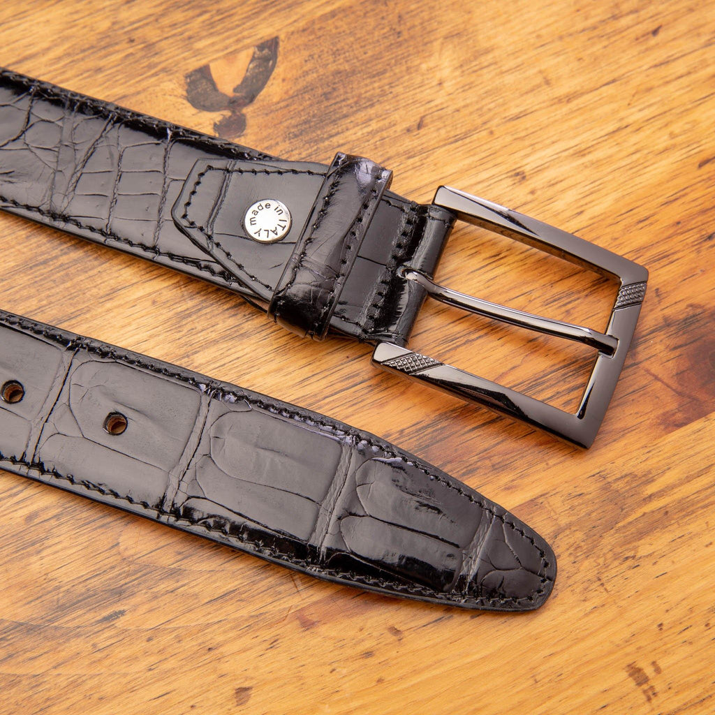 Up close picture of the Nickle buckle of C8099 Calzoleria Toscana Black Crocodile Belt on top of a wooden table