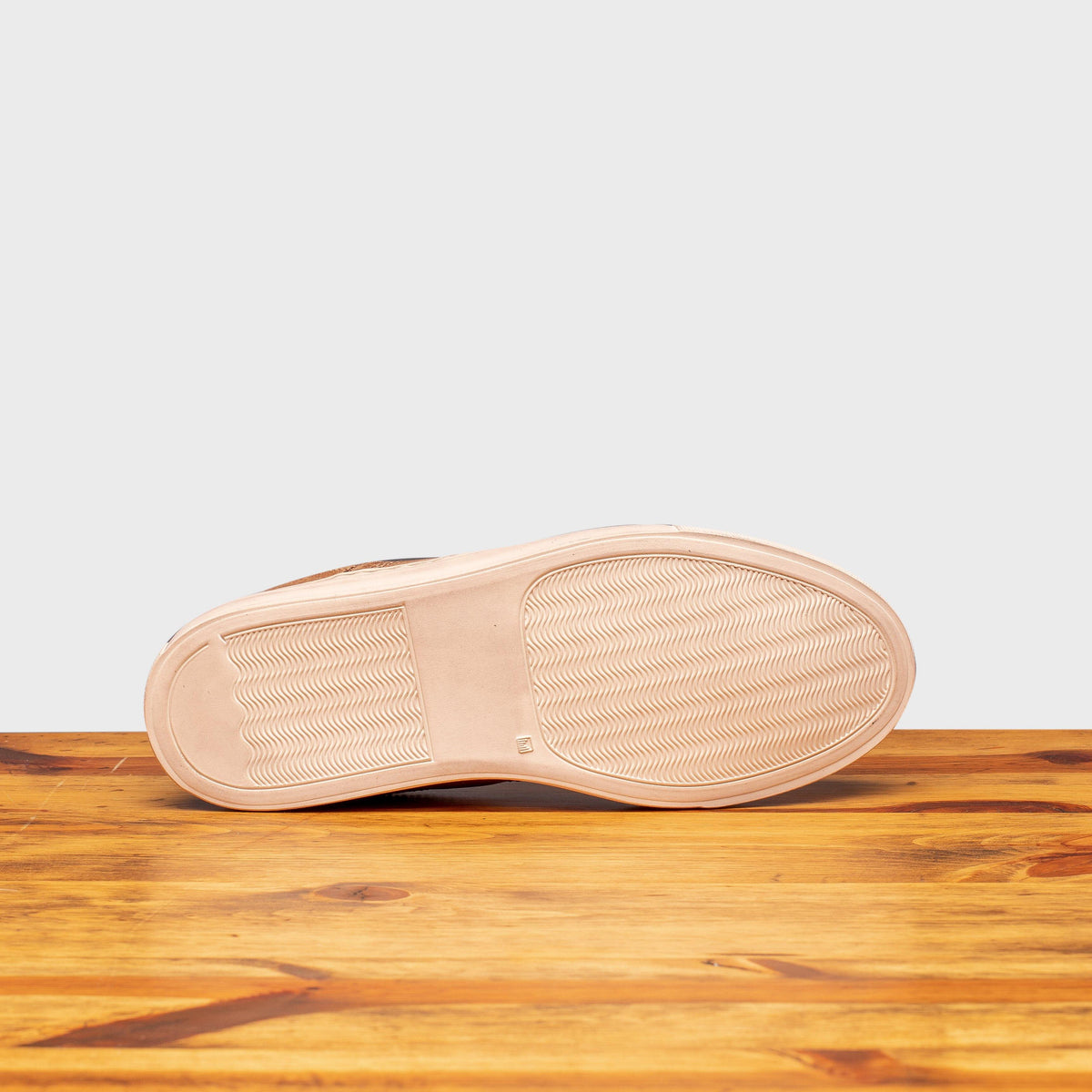 Outsole of Moor leather shoe on a wooden surface with a light gray background