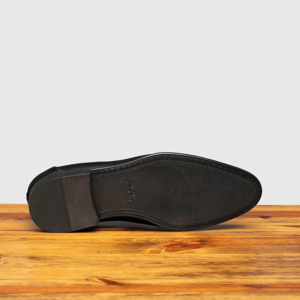 Full leather outsole of H614 Calzoleria Toscana Black Tassel Slip-On on top of a wooden table