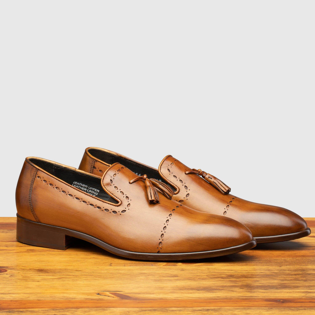 Profile of H614 Calzoleria Toscana Chestnut  Tassel Slip-On on top of a wooden table