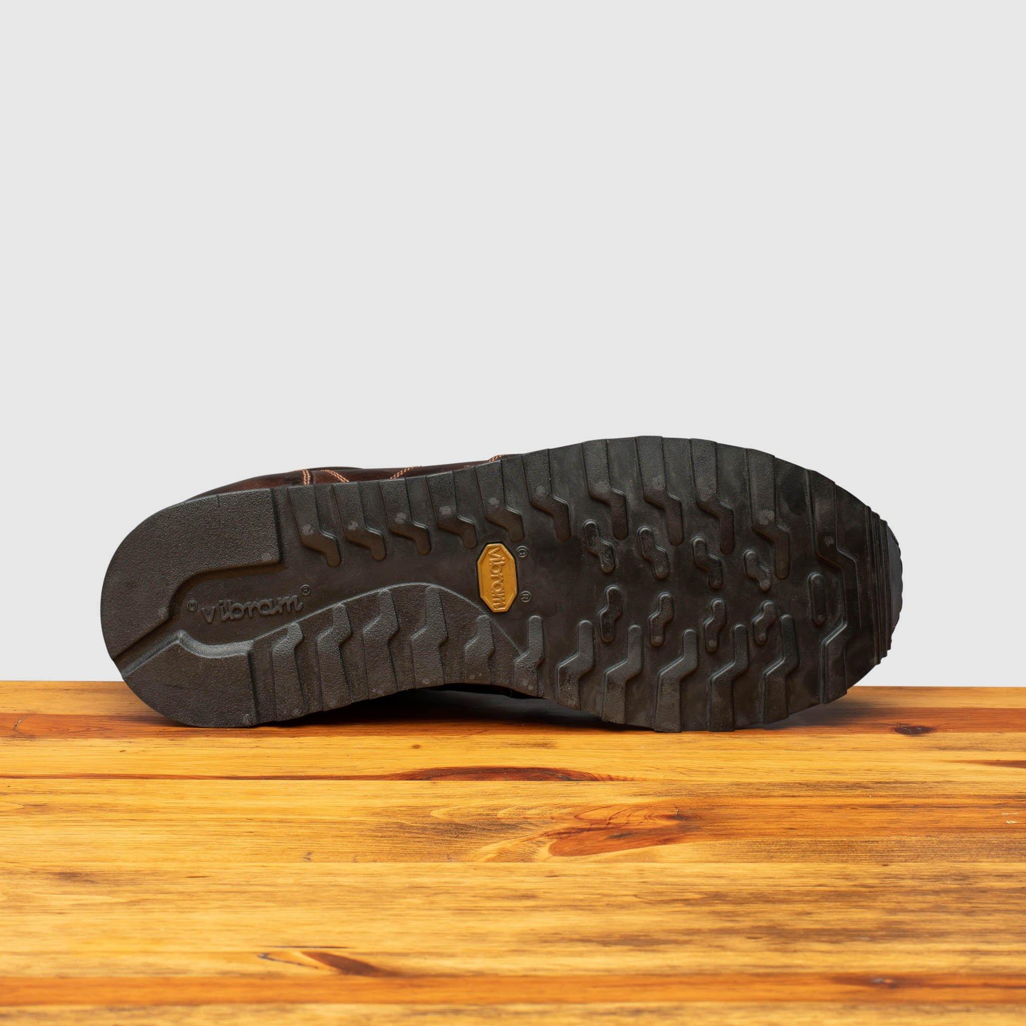 Full  Rubber Vibram outsole of H703 Calzoleria Toscana Dark Brown Sixty Seven Runner on top of a wooden table