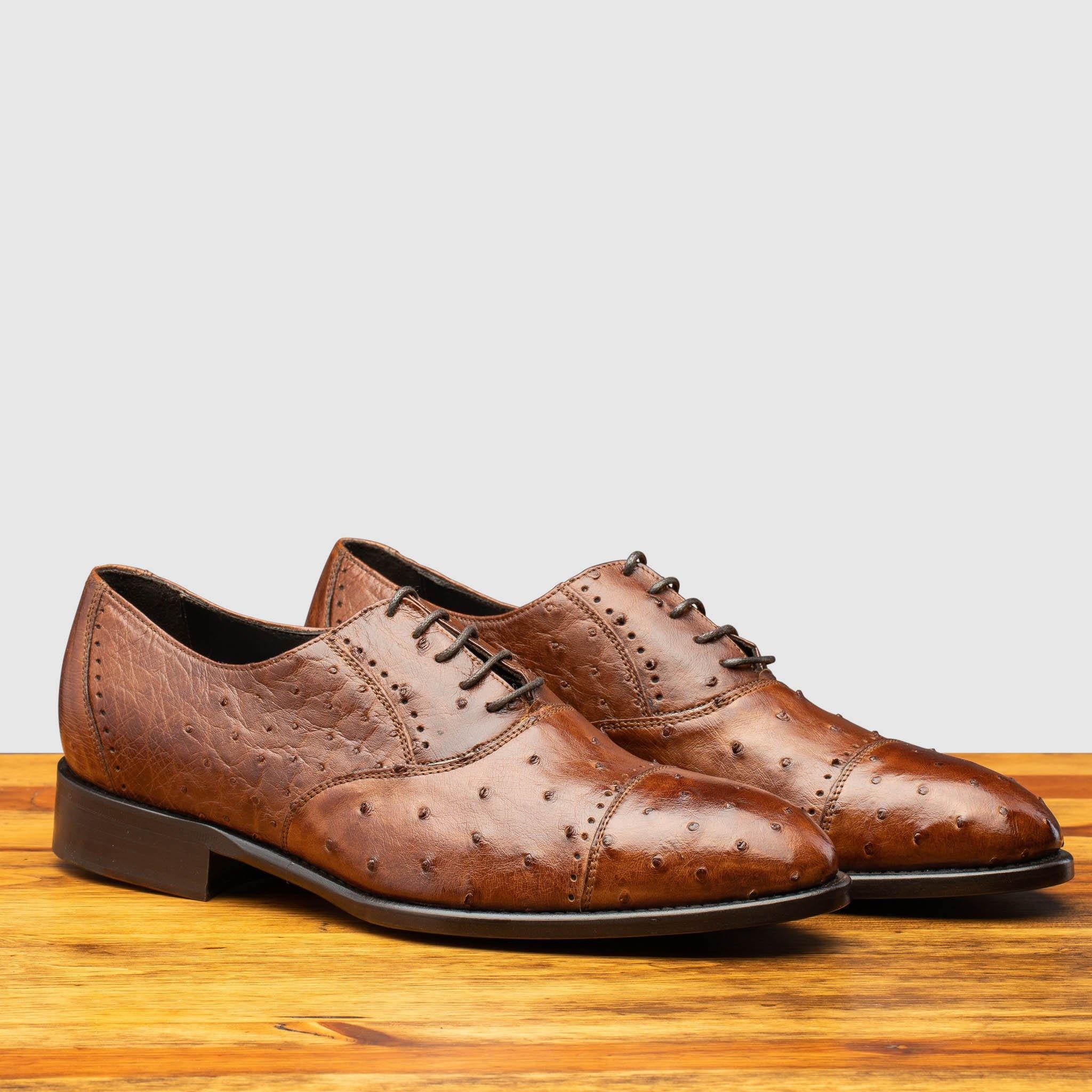 Pair of H777 Calzoleria Toscana Cognac Ostrich Cap Toe on top of a wooden table