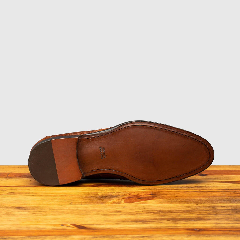 Full leather outsole of H777 Calzoleria Toscana Cognac Ostrich Cap Toe on top of a wooden table