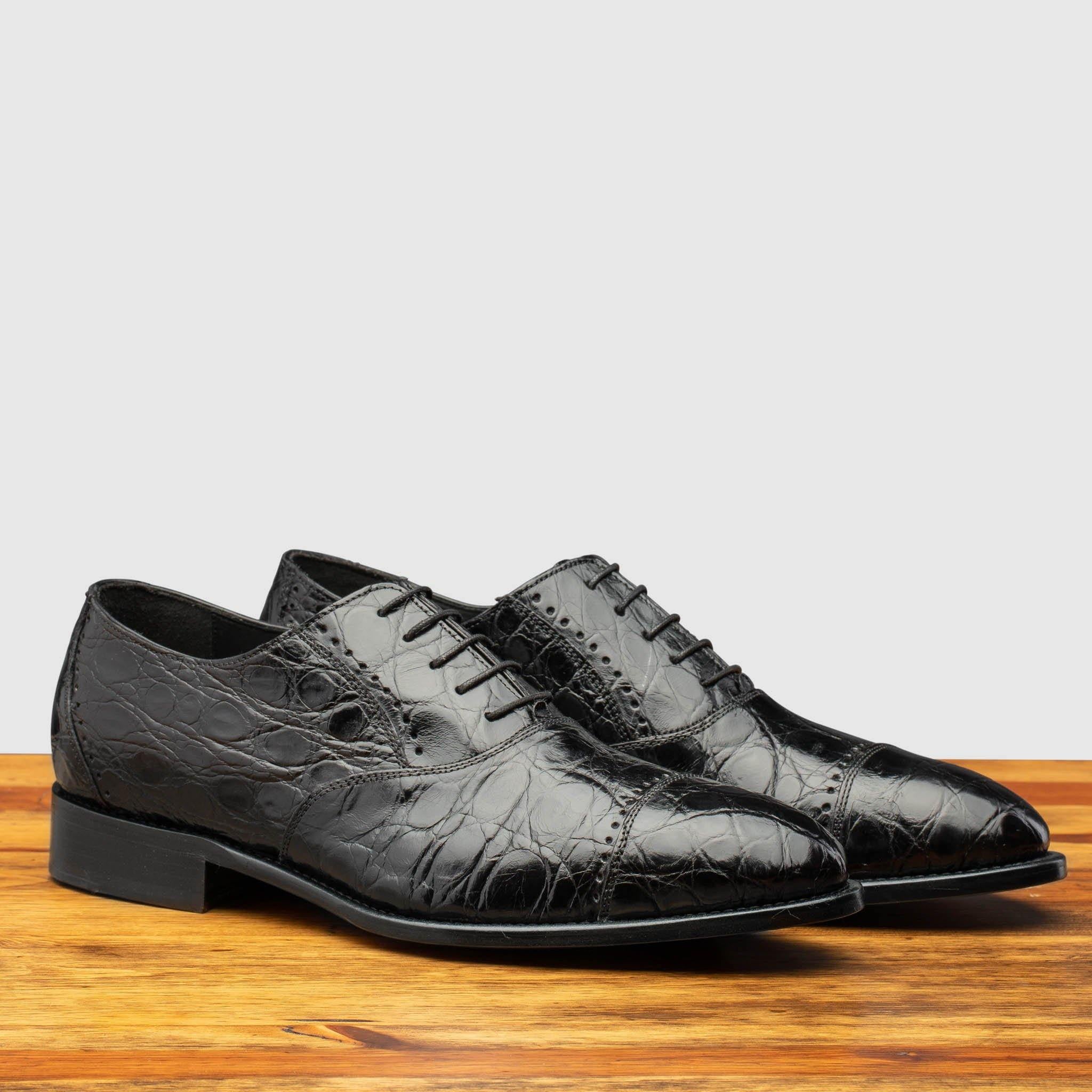 Pair of H779 Calzoleria Toscana Black  Silver Flanks Cap Toe on top of a wooden table