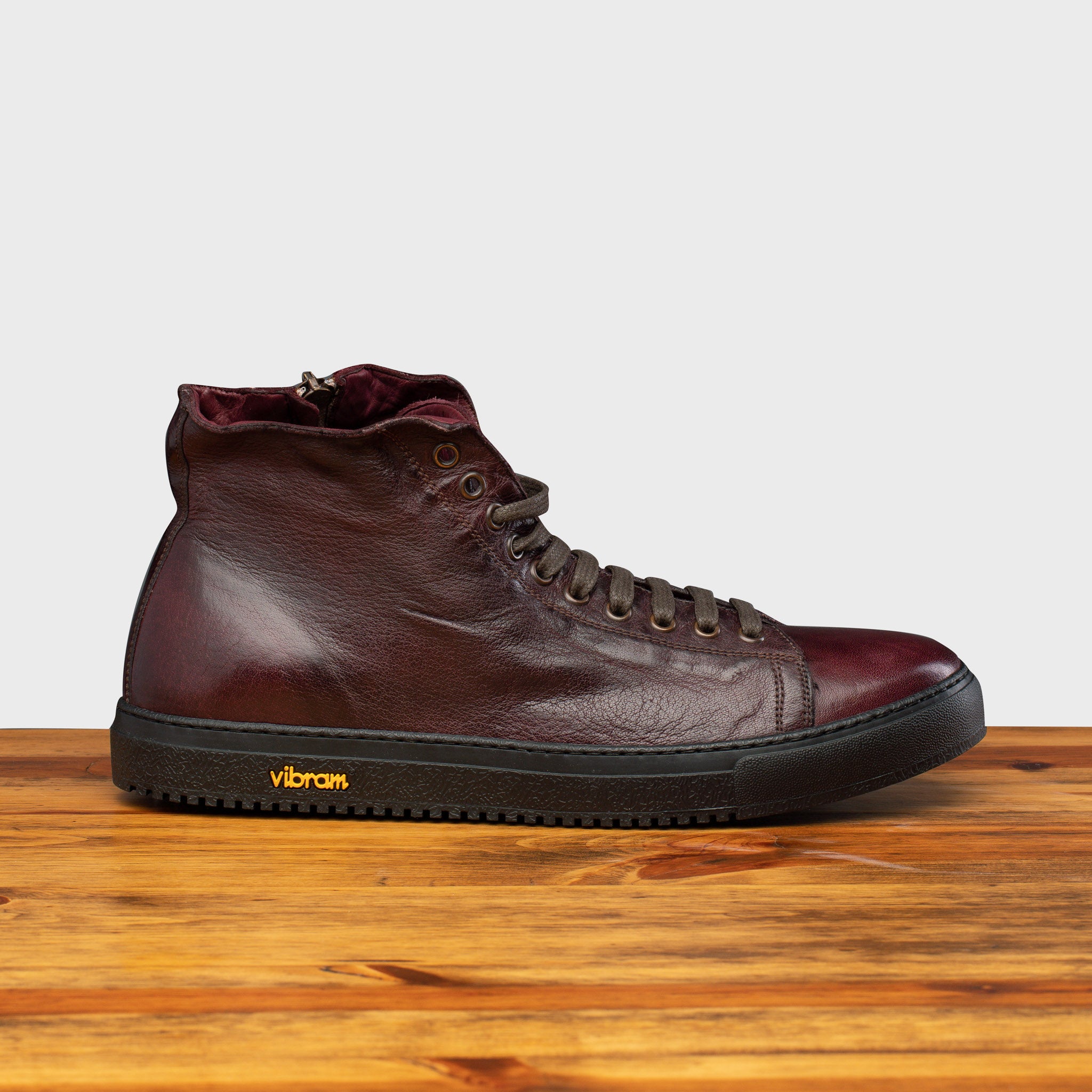 Side profile of H883 Calzoleria Toscana Liver High Top Benso Sneaker on top of a wooden table