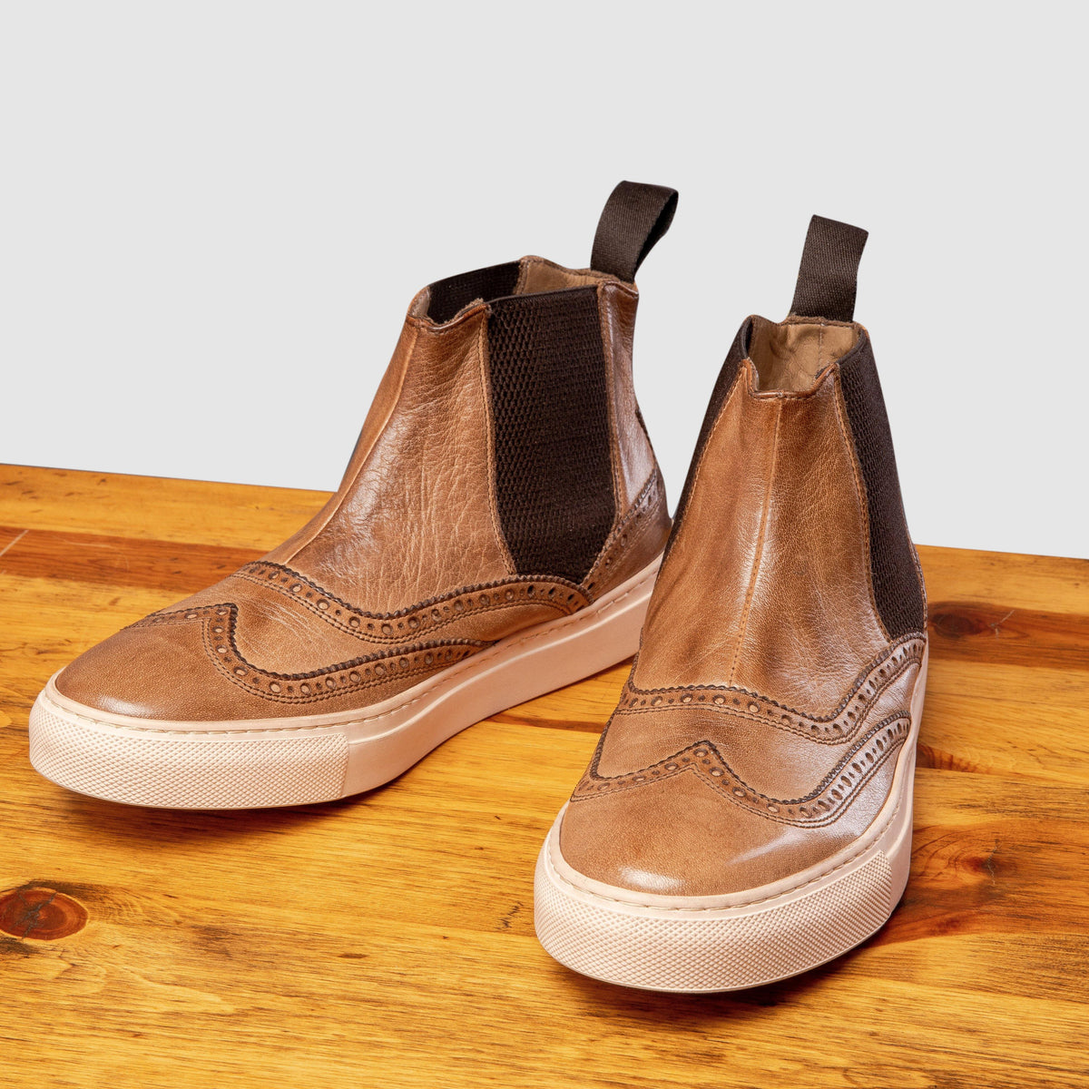 Pair of Moor leather shoe on a wooden surface with a light gray background