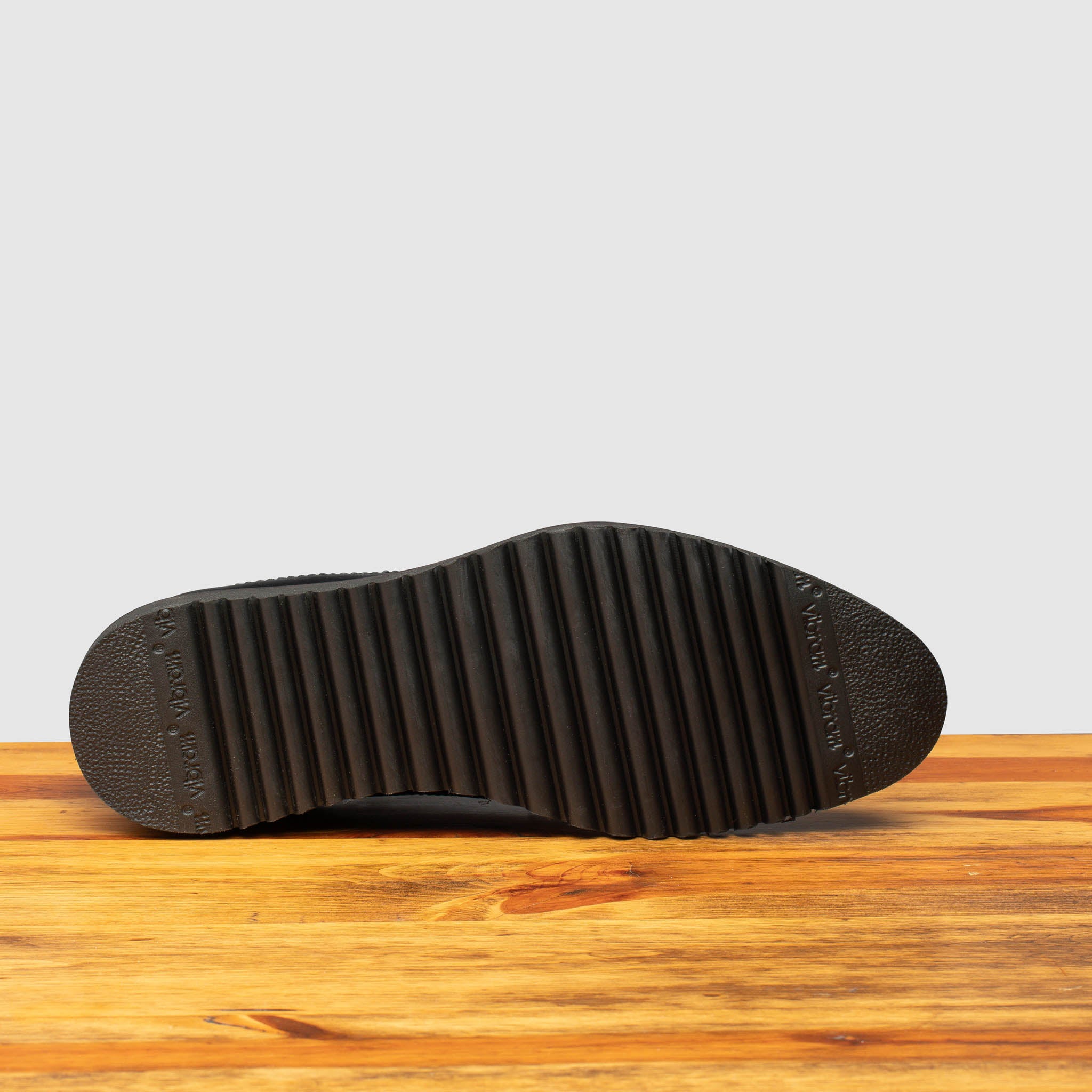 Full Rubber Vibram Outsole of Q400 Calzoleria Toscana Black Agos Blucher on top of a wooden table