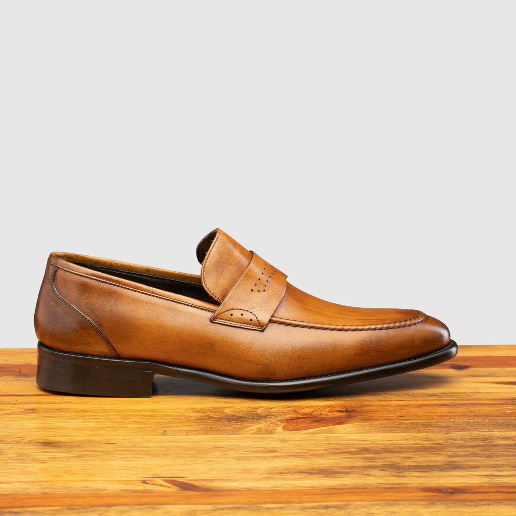 Side profile of Q540 Calzoleria Toscana Chestnut Wholecut Slip-On on top of a wooden table