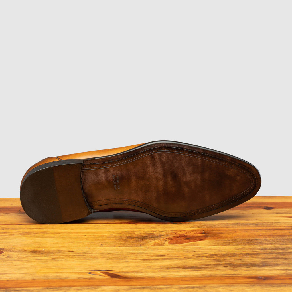 Full leather outsole of Q540 Calzoleria Toscana Chestnut Wholecut Slip-On on top of a wooden table