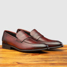 Pair of Q540 Calzoleria Toscana Burgundy (Porpora) Wholecut Slip-On on top of a wooden table