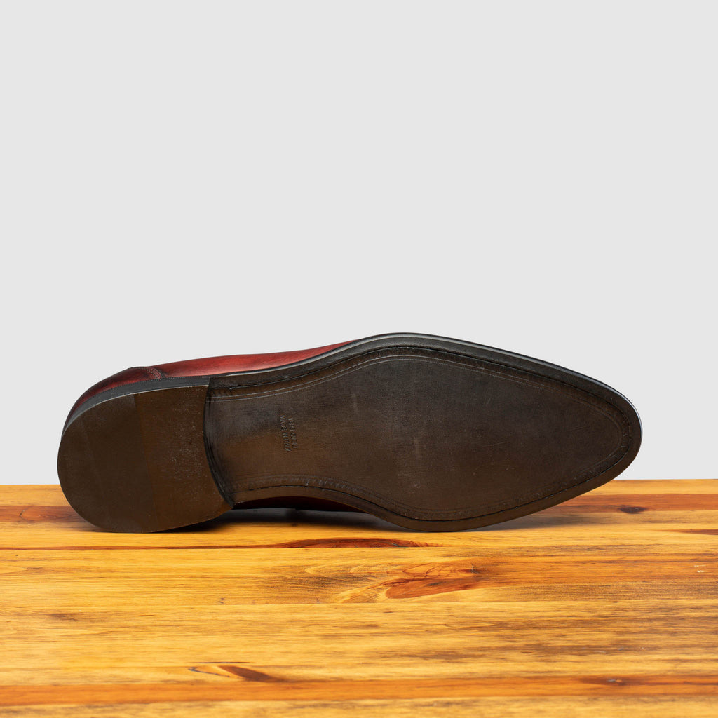 Full leather outsole of Q540 Calzoleria Toscana Burgundy (Porpora)  Wholecut Slip-On on top of a wooden table