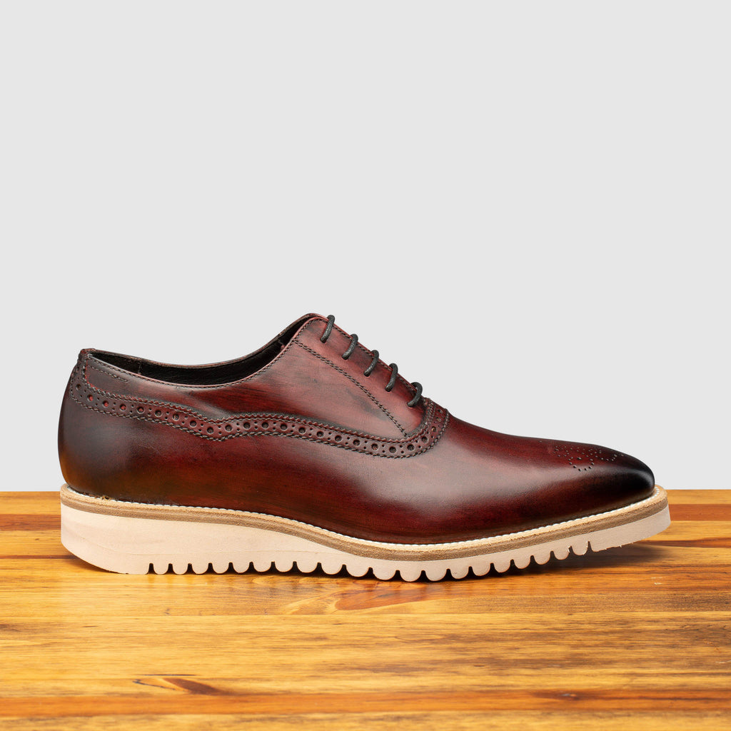 Side profile of Q548 Calzoleria Toscana Burgundy (Porpora) Onice Two Piece Oxford on top of a wooden table