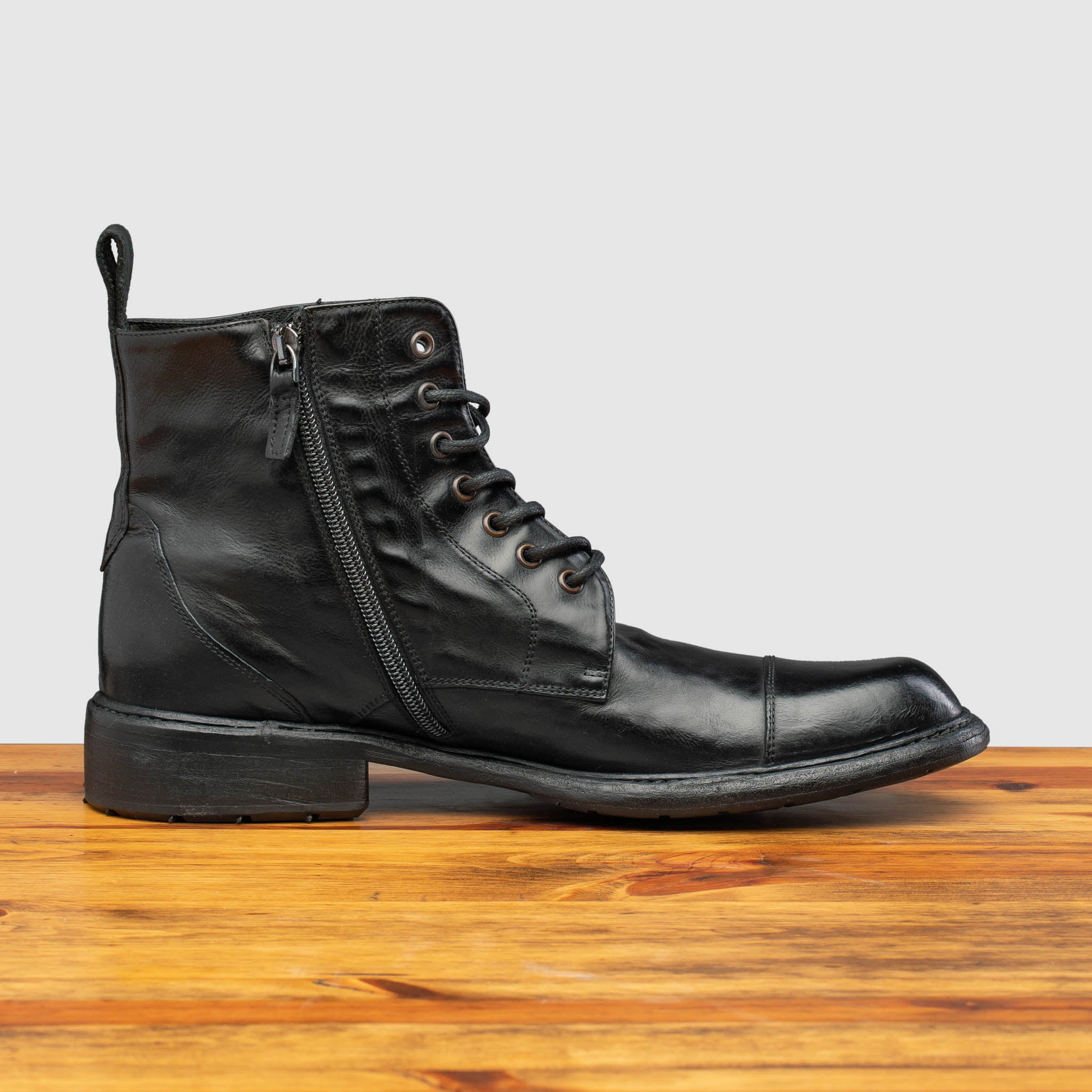 Side profile of Q549 Calzoleria Toscana Black Combat Boot on top of a wooden table