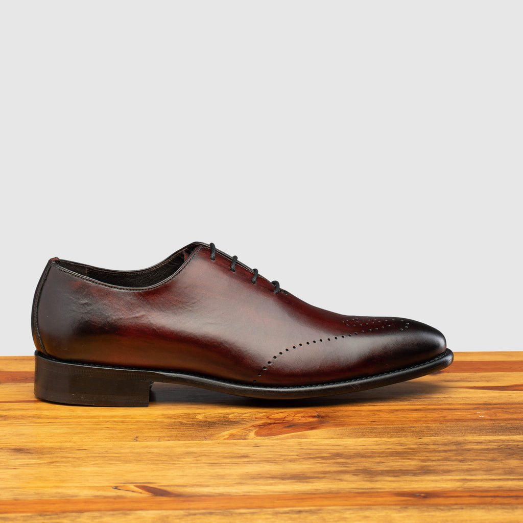 Side profile of Q550 Calzoleria Toscana Burgundy (Porpora) Burgundy Cayenne Calf Wholecut on top of a wooden table