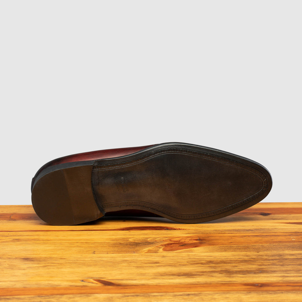 Full leather outsole of Q550 Calzoleria Toscana Burgundy (Porpora) Cayenne Calf Wholecut on top of a wooden table