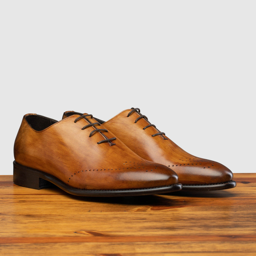Pair of Q550 Calzoleria Toscana Chestnut Cayenne Calf Wholecut on top of a wooden table