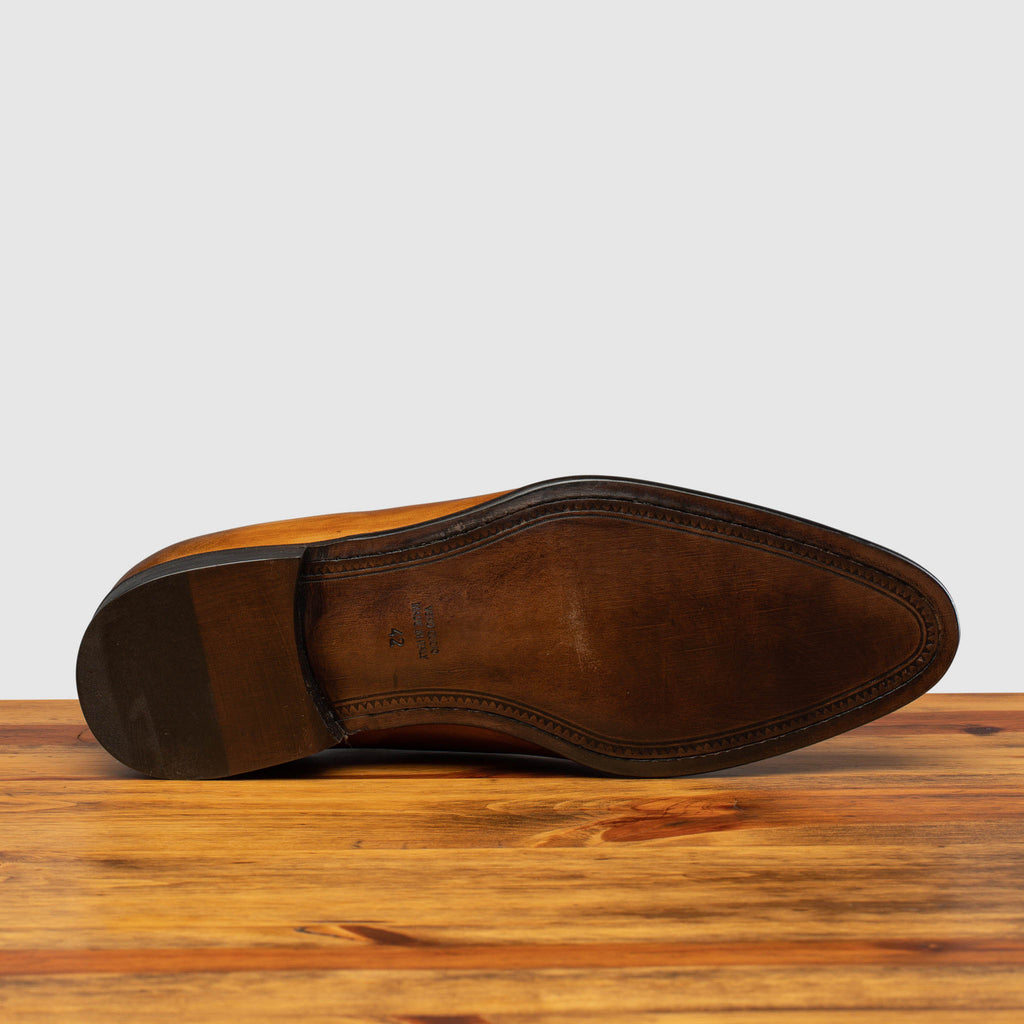 Full leather outsole of Q550 Calzoleria Toscana Chestnut Cayenne Calf Wholecut on top of a wooden table