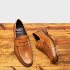 Pair of the Calzoleria Toscana Santor Collegiate Loafer in Dark Caramel showing the branded insole on top of a wooden table
