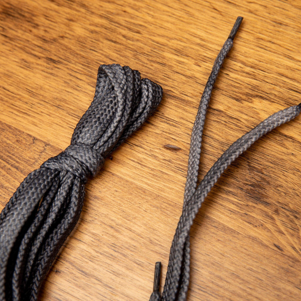 Up close pair of the Gray Dip-Dyed Cotton Calzoleria Toscana Laces on top of a wooden table
