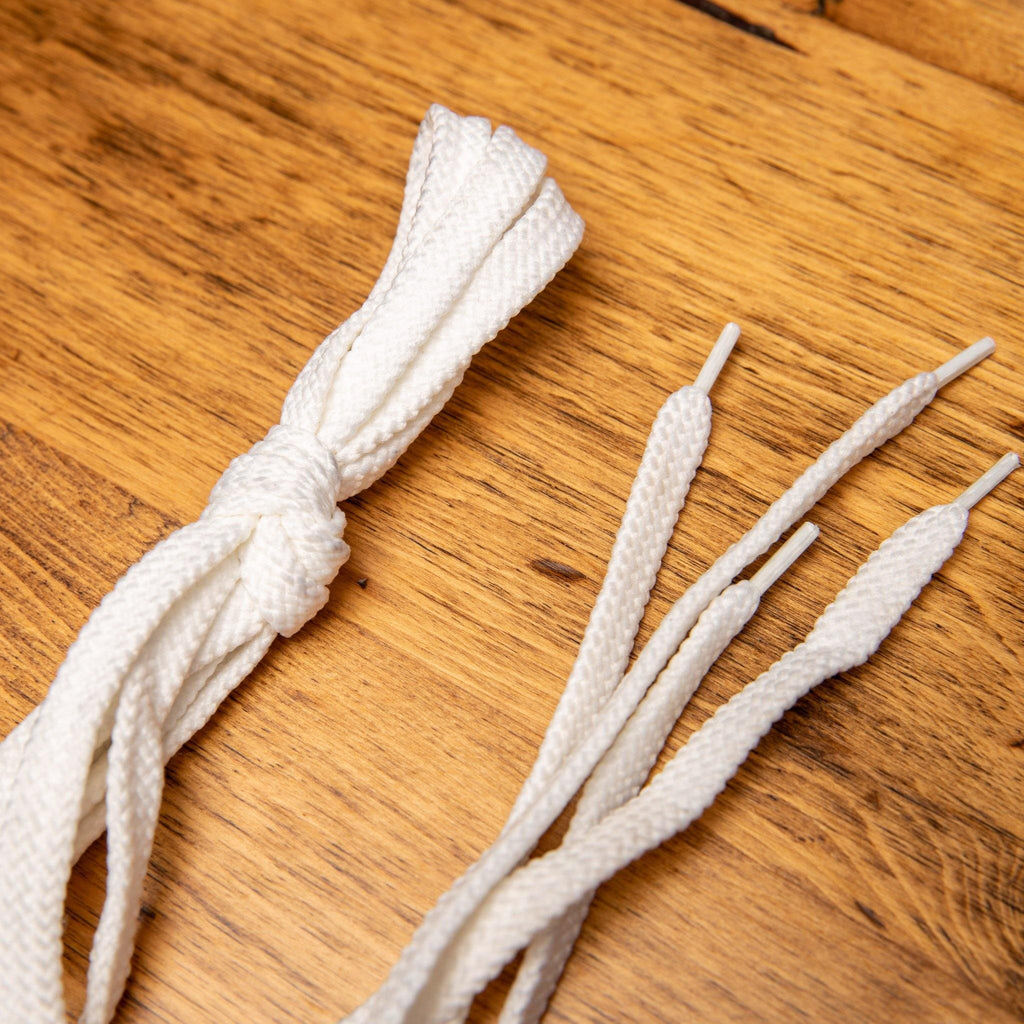 Up close picture of the pair of the white Dip-Dyed Cotton Calzoleria Toscana Laces on top of a wooden table