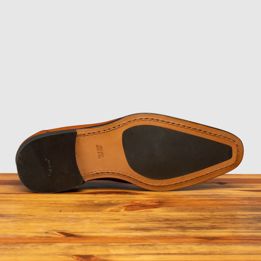 Injected Rubber Sole and Heel of Z993 Calzoleria Toscana Dark Caramel David Tassel Slip-On on top of a wooden table